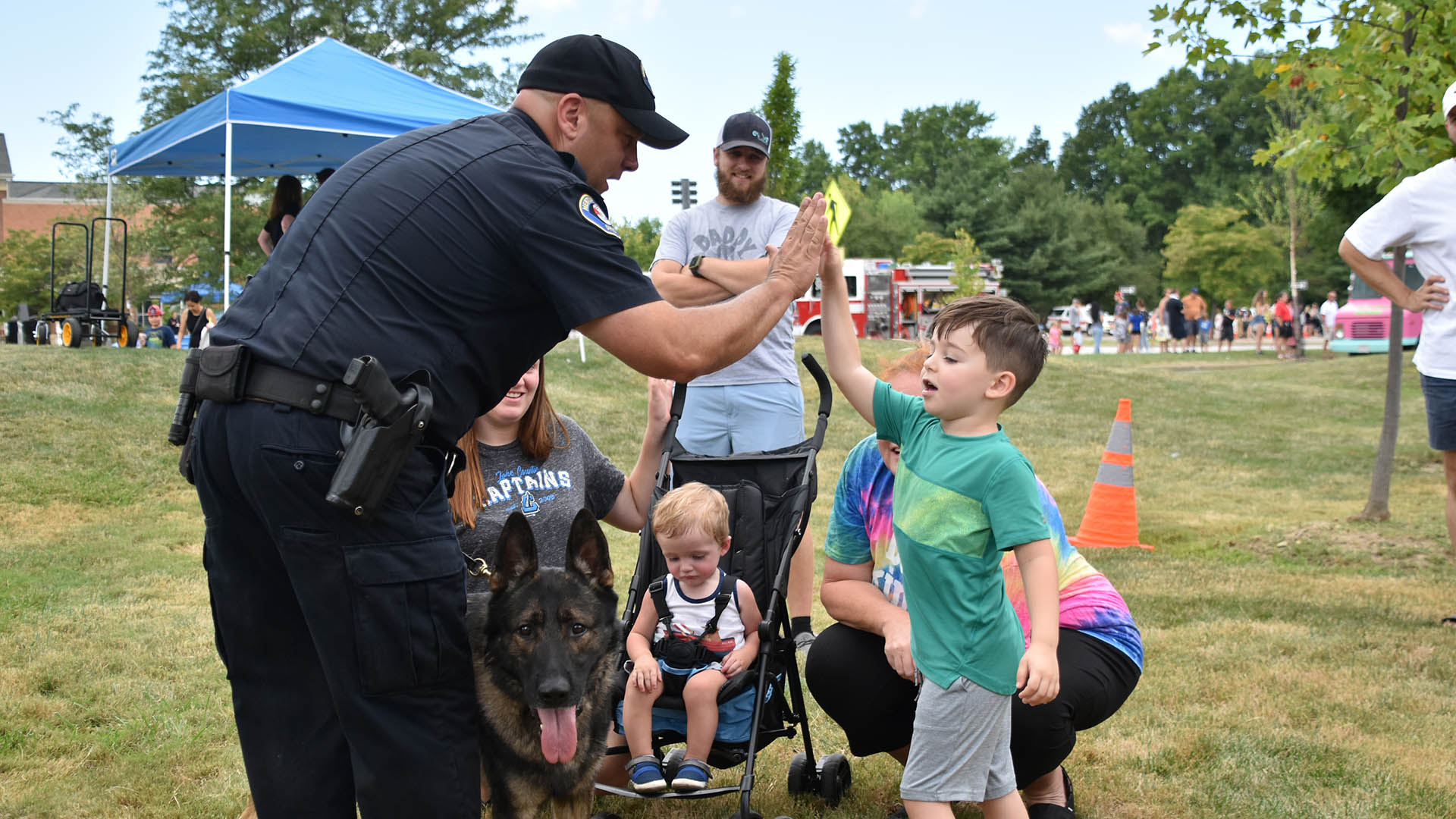 A child hi-fiving a police K9 officer at the Mentor Safety Forces Open House