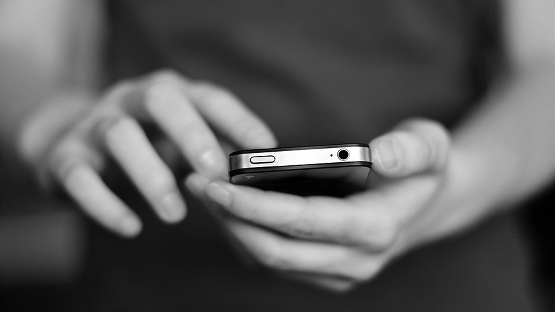 Person holding a mobile phone in response to receiving a text.