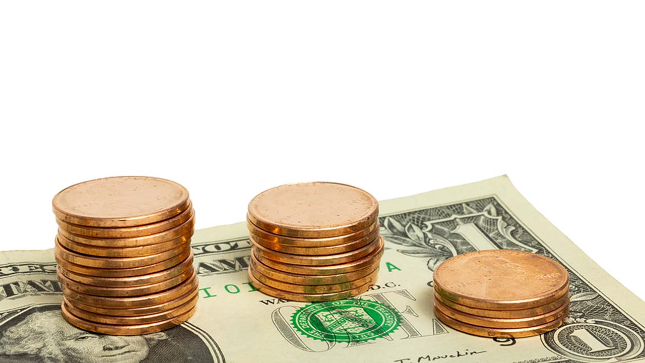 A dollar bill with pennies stacked on it.