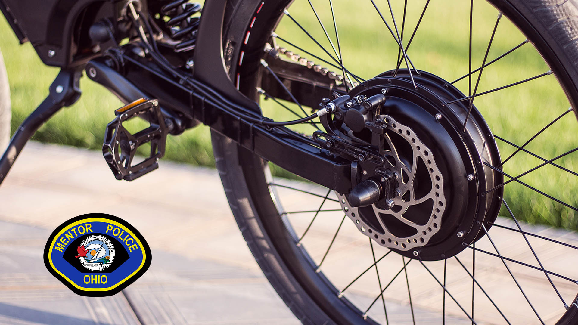 A close up of an eBike with the Mentor Police Patch overlayed on the bottom left.