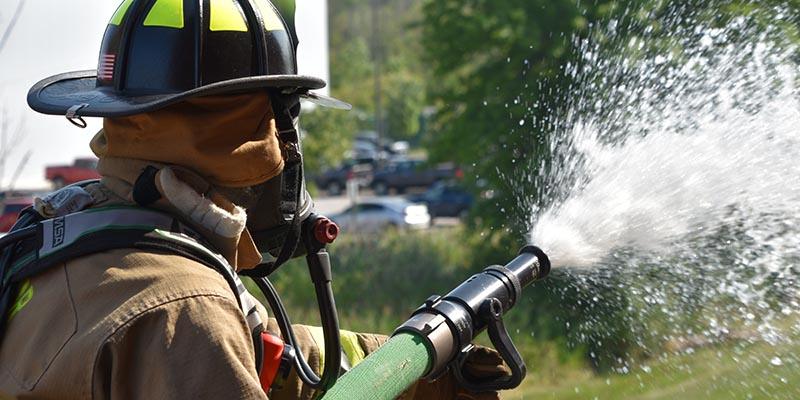 Mentor firefighter with hose
