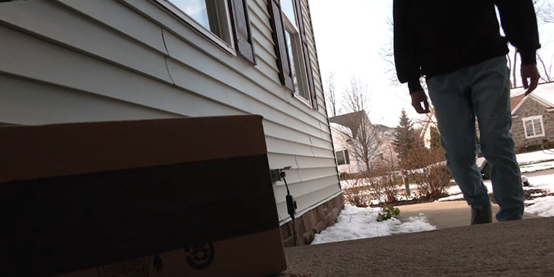 A porch pirate approaching a package.