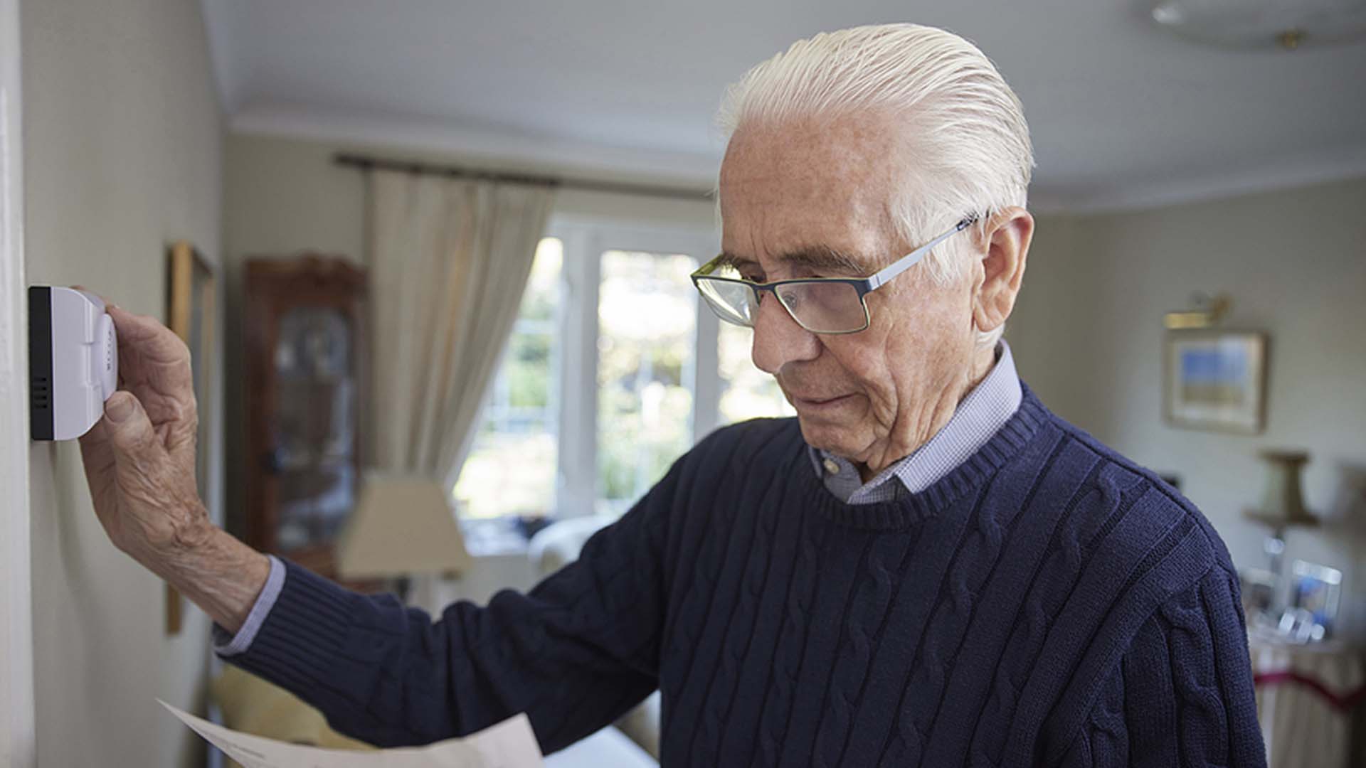 Image of person turning down thermostat.