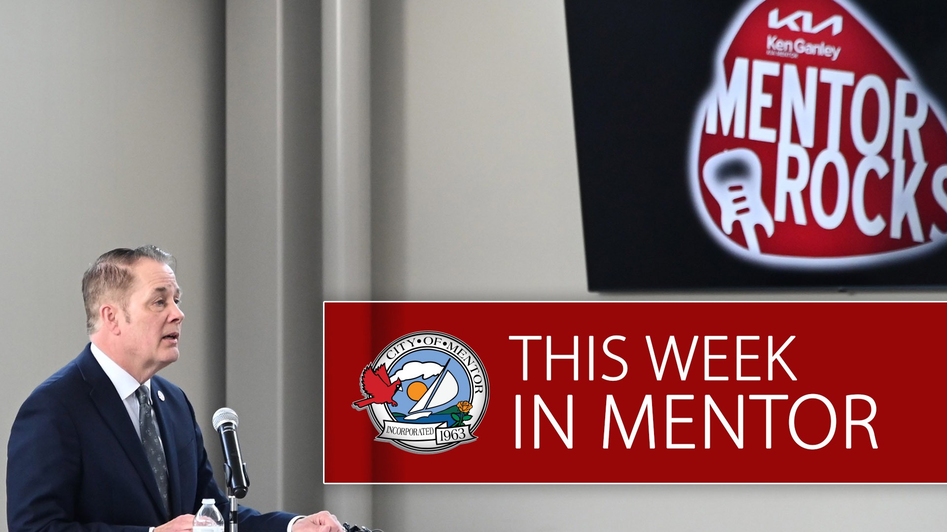 An image of Mentor City Manager Kenneth J. Filipiak speaking with the Mentor Rocks logo in the background. This Week in Mentor is superimposed in a red field in the foreground.